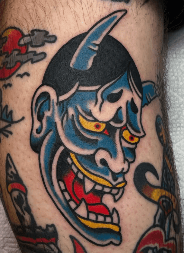 Tattoo of a horned laughing demon's head.