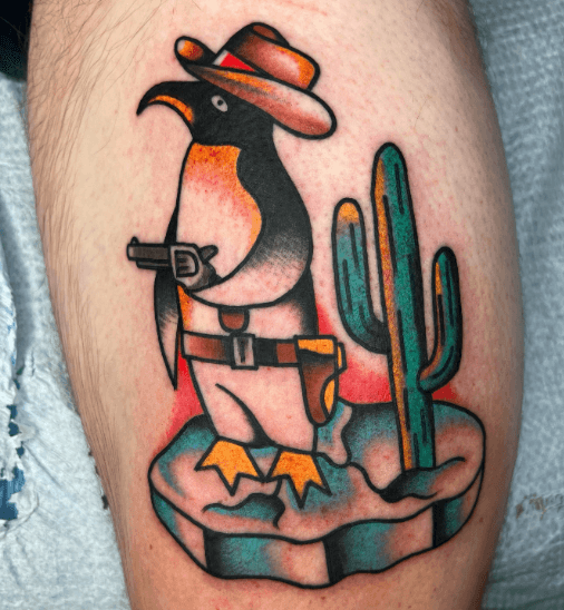 Tattoo of a penguin dressed as a cowboy with a guns.