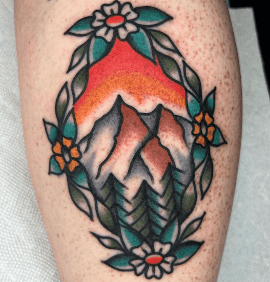A tattoo of a mountain landscape framed in flowers.