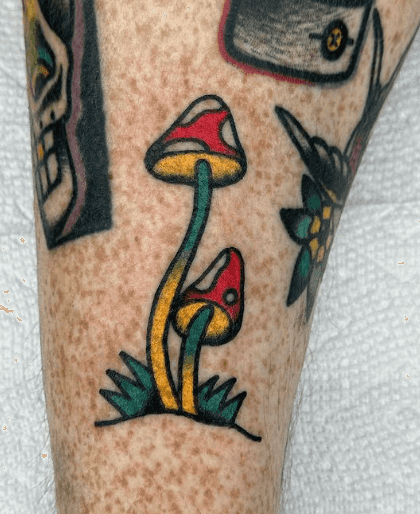 A tattoo of a pair of mushrooms growing from a patch a grass.
