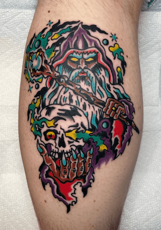 Tattoo of a wizard holding a skull.